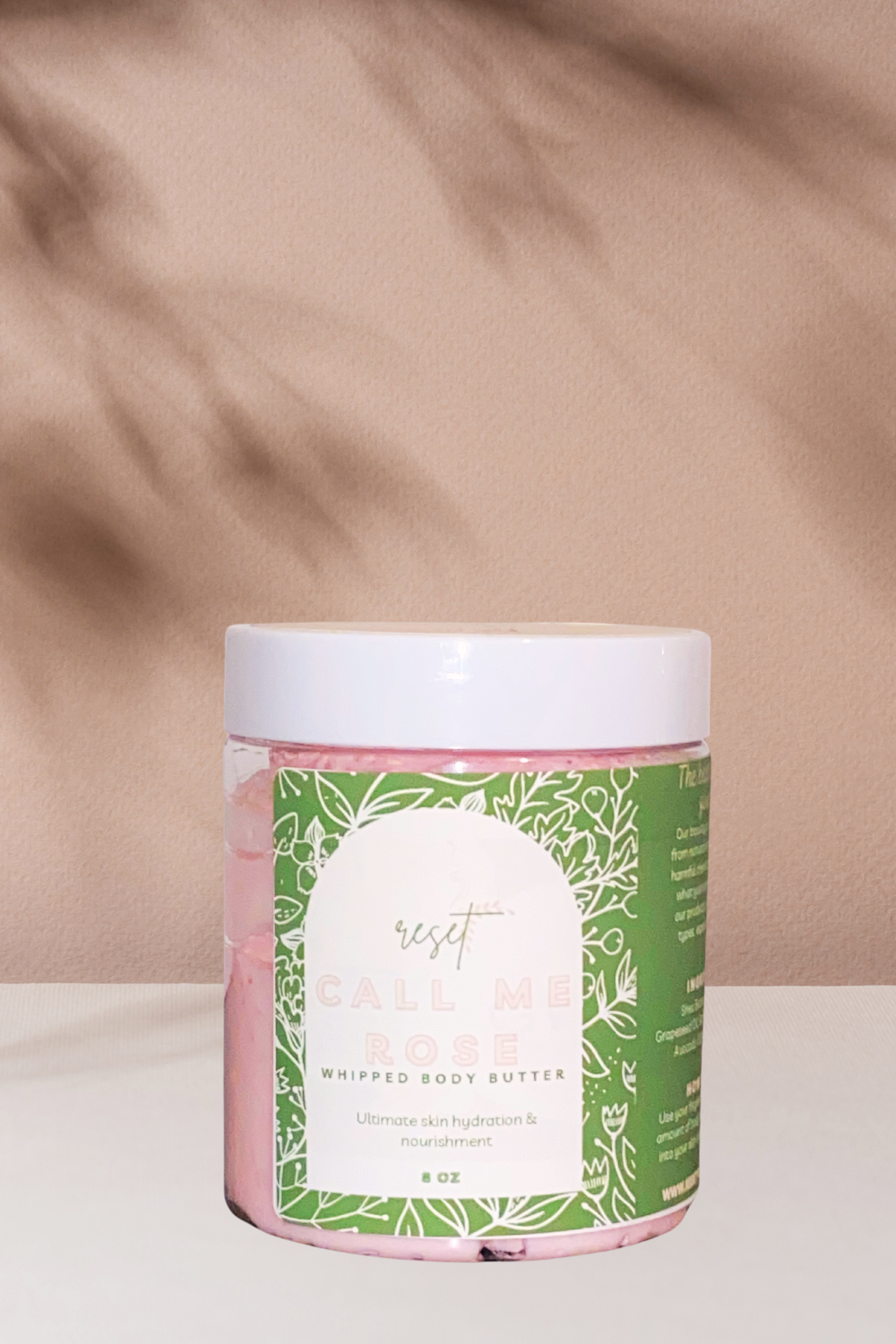 pink colored body butter in an 8oz jar on a nude table with a nude background